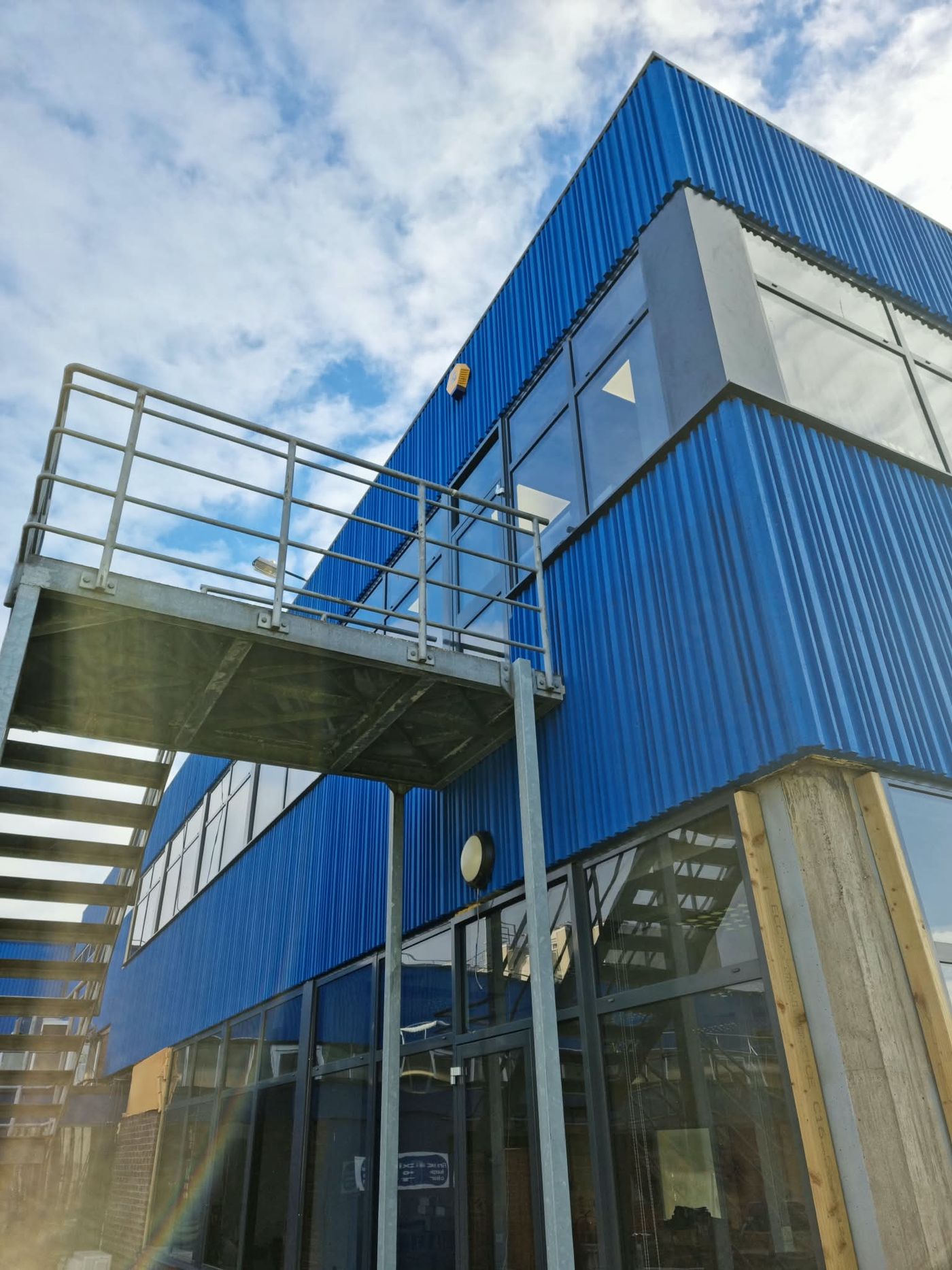 Blue-clad commercial building with aluminium ribbon glazing and ground-floor curtain walling